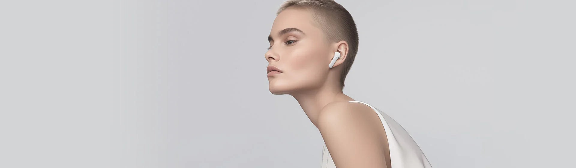 白いワイヤレスイヤホンを装着したショートヘアの女性のプロフィール写真。 minimalist なデザインと高級感が特徴的な最新テクノロジー製品。